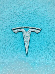 tesla logo on blue tesla vehicle that is wet